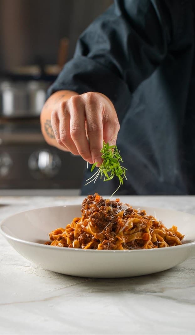 Tagliatelle being garnished by hand, by Trés Amis